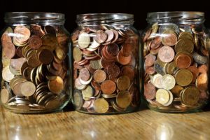 Three pots of saved coins depicte as money saving achieved through energy conservation