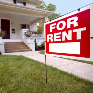 A sign board outside the house with "For Rent" written on it